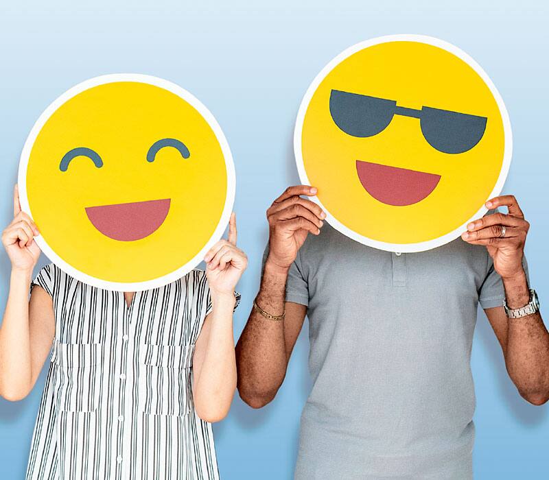 people holding smiley faces up to their faces