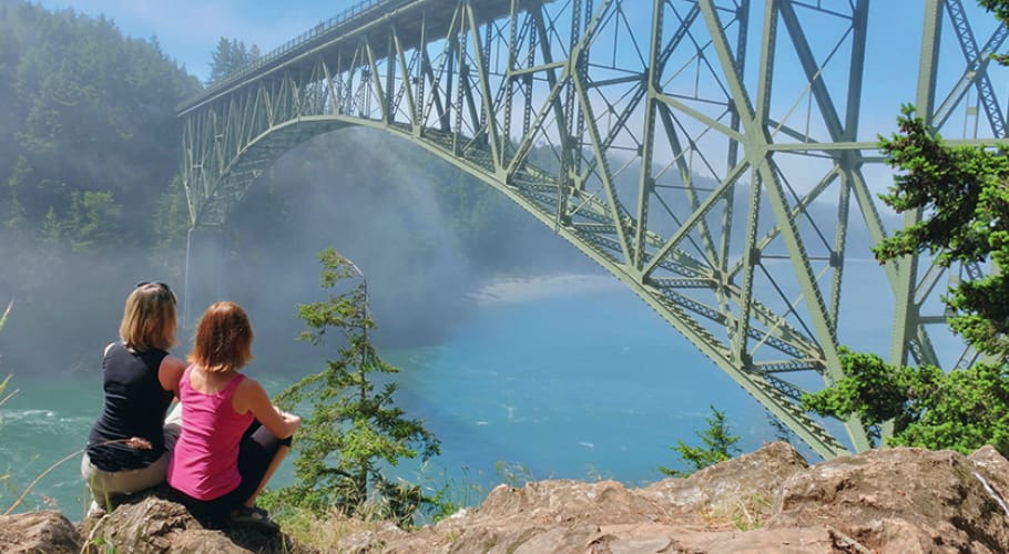 two people sitting by a bridge