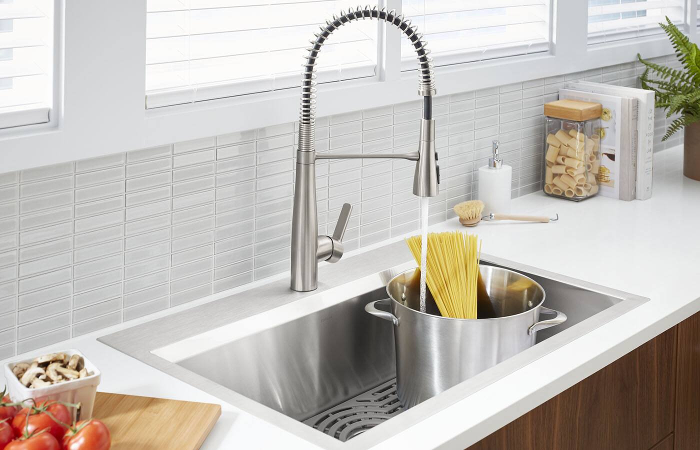 Natural, bright light illuminates bathroom adorned with white porcelain subway tiles on the back wall and light-brown hardwood flooring. A gleaming Kohler porcelain white toilet, porcelain white pedastal sink with nickle-plated faucet fixtures provide the main focus.