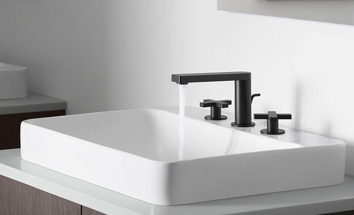Ultra modern-looking Kohler sink. The sink is a round, glass shallow bowl type, with seaform green hues cast by the thickness. It rest upon a marble-topped vanity and features a chrome faucet fixture.