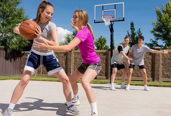 Four teenagers play a basketball outside. 